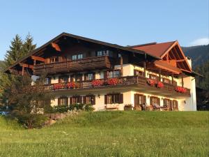 una casa grande en una colina con un campo verde en Ferienwohnung Winklblick en Reit im Winkl