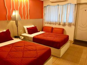 2 Betten in einem Hotelzimmer mit orangefarbenen Wänden in der Unterkunft Highway Hotel in Chiang Mai