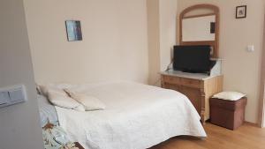 een slaapkamer met een wit bed en een televisie bij Apartamenty Cecylia in Międzyzdroje