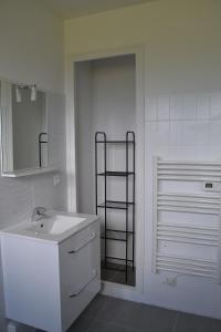 Baño blanco con lavabo y estante en chez juliette, en Mauléon