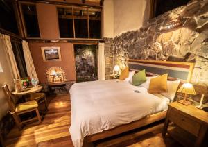 een slaapkamer met een groot bed en een stenen muur bij Sacred Dreams Lodge in Urubamba