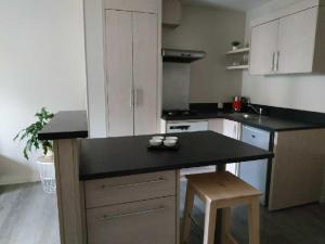 cocina con armarios blancos y encimera negra en appartement avec terrasse, en Aurillac
