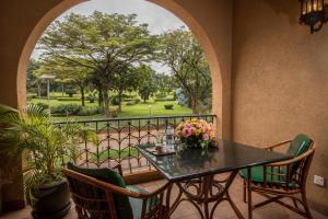 una mesa con un jarrón de flores en el balcón en Speke Hotel 1996 Ltd en Kampala