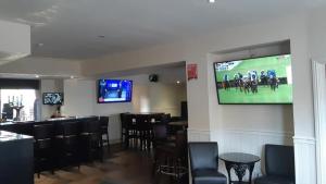 um bar com cadeiras pretas e uma televisão na parede em dalesman hotel em Darlington