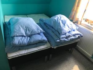 2 Kissen auf einem Bett in einem Zimmer mit Fenster in der Unterkunft Det lille gule hus in Trongisvágur