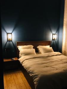 a bedroom with a large bed with two lights on it at Apartment Riverside in Kutaisi