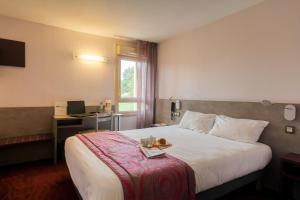 a hotel room with a bed with a tray of food on it at Brit Hotel Les Evens in Saint-Saturnin