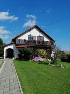 a white house with a balcony on a lawn at House Mihaela&nina in Seliste Dreznicko