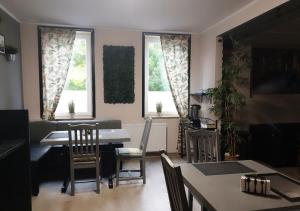 a living room with a table and chairs and two windows at Hotel Geismar in Göttingen