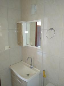 a white bathroom with a sink and a mirror at Suíte em Caraguá in Caraguatatuba