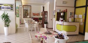 un restaurant avec une table et des chaises ainsi qu'une cuisine dans l'établissement Hotel La Falena, à Cervia