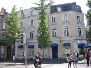 Un edificio en una calle de la ciudad con gente caminando frente a él. en Le Royalty, en Angers