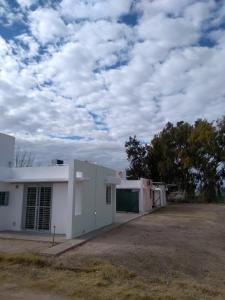 un edificio blanco con un cielo nublado en el fondo en Cabañas Plaza Norte en San Martín