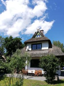 Darßer Strandgut - Haus Butzek في ارنشوب: منزل به سقف من القش مع طاولة وكراسي