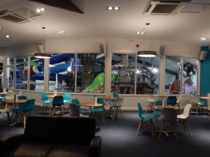 uma sala de espera com mesas e cadeiras e um parque infantil em Flamingo Land - Beech Grove B11a em Kirby Misperton