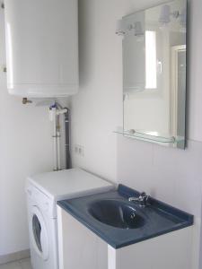 a bathroom with a sink and a washing machine at Gîtes des Campanes in Saint Alban Auriolles