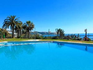 une grande piscine avec des palmiers et l'eau dans l'établissement VILLA BAHIA AZUL, à Estepona