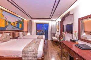 a hotel room with two beds and a desk at Fivitel Hoi An Hotel in Hoi An
