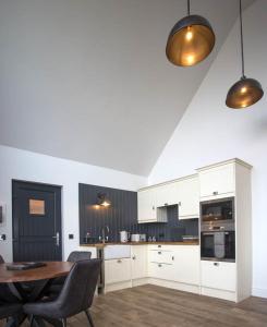 a kitchen with white cabinets and a table and chairs at Creag Moine Luxury Self Catering in Kensaleyre