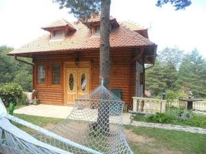 una casa di tronchi con un'amaca di fronte di Apartmani Smigic Divcibare a Divčibare