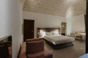 a bedroom with a bed and a chair and a tub at Euvodia Luxury Rooms in Matera
