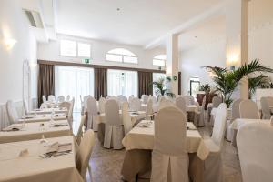 une salle de banquet avec des tables blanches et des chaises blanches dans l'établissement Hotel Falcone, à Vieste