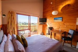 um quarto com uma cama grande e uma varanda em Ocean View Chalets em Marahau