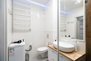 La salle de bains blanche est pourvue d'un lavabo et de toilettes. dans l'établissement Apartament T.LOVE NOVA 2, à Szczecin