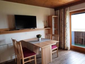 comedor con mesa, sillas y TV en Ferienwohnung Bernsteiner, en Iselsberg