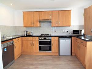 a kitchen with wooden cabinets and stainless steel appliances at 67c The Mews in Newport