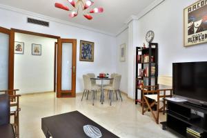 a living room with a television and a table and chairs at Apartamento Centrum Córdoba con Parking in Córdoba