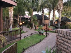 a garden with palm trees and a brick walkway at Country Lodge in Upington