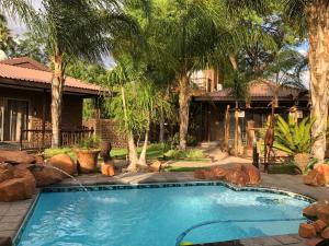 a swimming pool in front of a house with palm trees at Country Lodge in Upington
