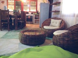 a living room with two wicker chairs and a kitchen at La Casa de Juan in Holbox Island