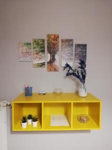 un meuble jaune contre un mur orné de peintures. dans l'établissement Anchida casa vacanze, à Enna