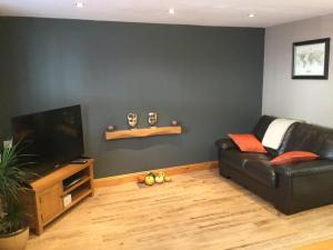 een woonkamer met een zwarte leren bank en een flatscreen-tv bij 6 beili priory in Abergavenny
