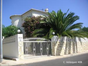 a white fence with palm trees in front of a house at Frente al Mar - Velazquez in Oliva