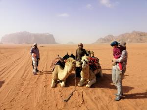 a group of people standing in the desert with camels at Omar Ghazi Camp in Wadi Rum