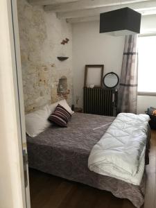 a bedroom with a bed and a stone wall at Chez leo in Marboué