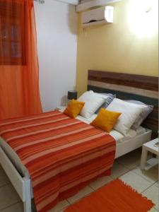 ein Schlafzimmer mit einem Bett mit orangefarbenen und weißen Kissen in der Unterkunft Villa Ponm Kann'L in Deshaies