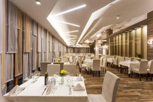 a dining room with white tables and chairs at Perelik Hotel in Pamporovo