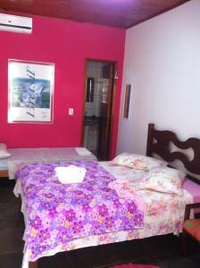 a bedroom with two beds and a pink wall at MIAU Maison Internacional Alojamento Urbano in Foz do Iguaçu