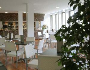 a dining room with tables and white chairs and a plant at Hotel Giubileo in Pignola