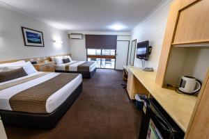 una camera d'albergo con due letti e una televisione di Reef Gateway Hotel ad Airlie Beach