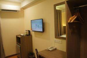 um quarto com uma televisão numa parede com uma mesa em LABUAN JATI HOTEL em Labuan