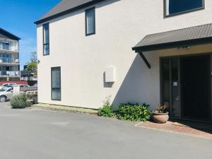 a white house with a driveway and a door at Salisbury Apartment - Christchurch Holiday Homes in Christchurch