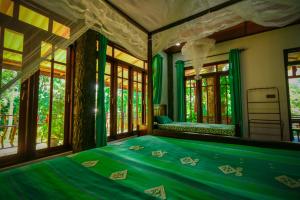 a bedroom with a bed with green sheets and windows at Happy Horizon Home Stay in Ella