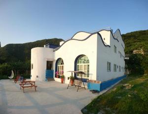 a white building with tables and benches in front of it at Green Island Starry Night Hostel in Green Island +19 photos