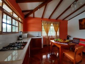 a kitchen with orange walls and a table with a bowl of fruit at Suymar Ecolodge Galapagos in Puerto Ayora