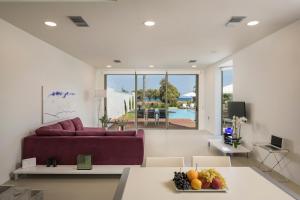 Blue Sea Luxury Villa في ماليم: غرفة معيشة مع أريكة أرجوانية وطاولة مع فاكهة